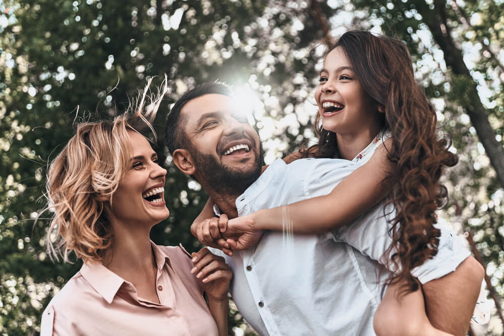 Family, woman, man and young girl, outside smiling and laughing